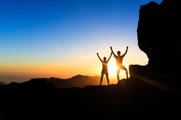 couple with arms raised in setting sun
